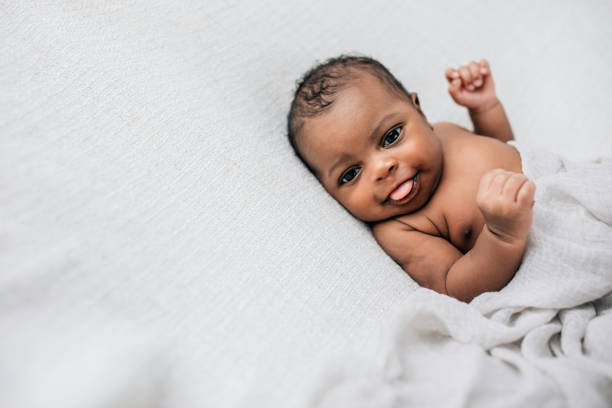 Beautiful African-American newborn little boy just a few weeks old swaddled in a cream colored soft blanket with copy space stock photo