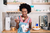 Beautiful African-American young woman eating her ordered lunch at home.