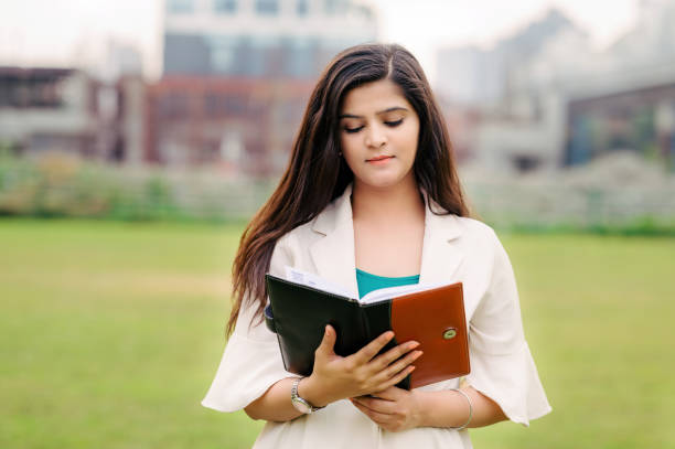 A beautiful Asian/ Indian girl is reading a book or diary in outdoor location. A beautiful Asian/ Indian girl is reading a book or diary in outdoor location. students stock pictures, royalty-free photos & images