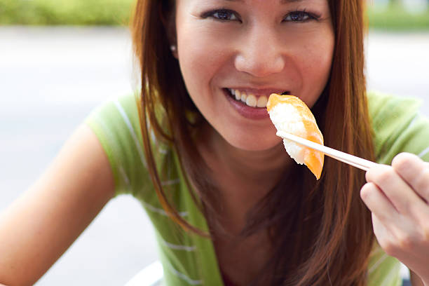 Beautiful Asian Woman Eating Sushi stock photo