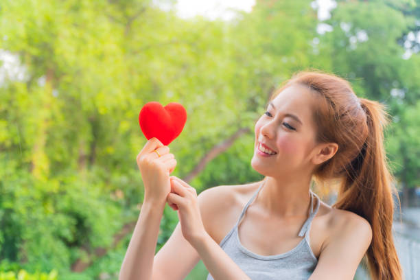 A beautiful Asian woman holds a red heart with happiness. love, happiness and people concept. stock photo