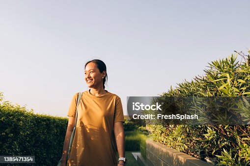 istock Beautiful Asian Woman in a Casual Yellow Dress Walking in the Park on a Sunny Day 1385471354
