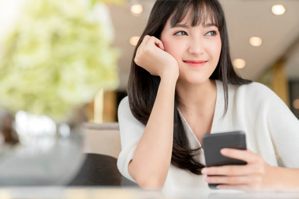 美しいアジアの女性長い黒髪の肖像画白いセーター幸せ笑顔と肯定的な思考 - スマホ　女性　日本人 ストックフォトと画像