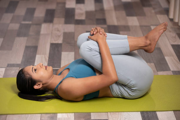 woman performing knees to chest pose to improve digestion