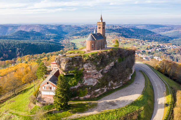 Beautiful autumn aerial view of St. Leon chapel dedicated to Pope Leo IX atop of Rocher de Dabo or Rock of Dabo, red sandstone rock butte, and Moselle-Vosges mountains and valleys. Lorraine, France Beautiful autumn aerial view of St. Leon chapel dedicated to Pope Leo IX atop of Rocher de Dabo or Rock of Dabo, red sandstone rock butte, and Moselle-Vosges mountains and valleys. Lorraine, France. lorraine stock pictures, royalty-free photos & images