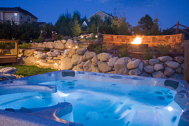 Beautiful Backyard Brilliant Blue hot tub in the foreground and awesome fire pit and landscaping in the background. Long exposure was taken at dusk with deep blue sky and time lapse of the fire pit. hot tub stock pictures, royalty-free photos & images