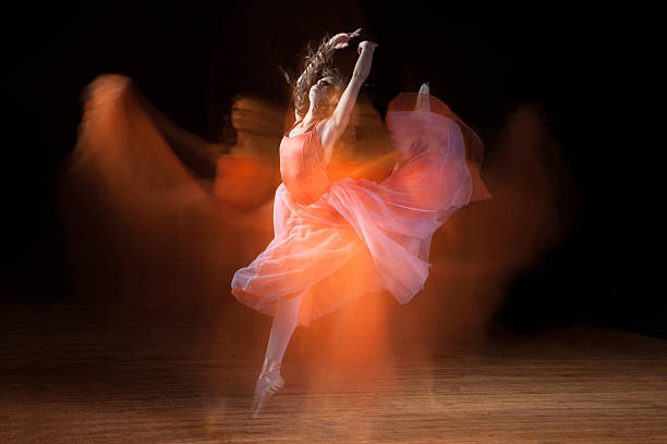 Beautiful Ballerina Dancing on Dark Stage with Ghosts Ballerina dancing on dark stage with ghostly images (single image capture). slow motion stock pictures, royalty-free photos & images