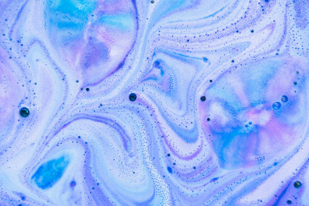 Beautiful bath bomb dissolves in blue, purple and pink colors in the water. Flat lay, top view, directly above. Abstract background stock photo