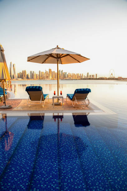 Beautiful beach in Dubai with 2 sun chairs and an umbrella. In the background is the skyline of Dubai Marina stock photo