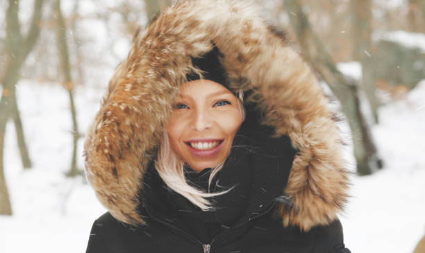 Beautiful blond woman in a winter parka A happy blonde woman in a parka with a hoodie on a windy winter day in Sweden. beautiful swedish women stock pictures, royalty-free photos & images