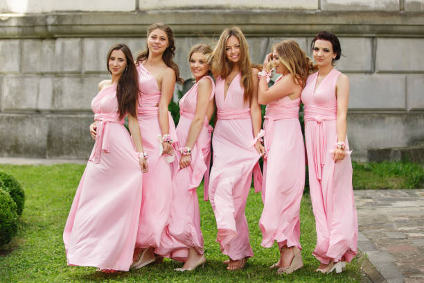 Beautiful bridesmaids in pink dresses posing and looking to camera at wedding day. Group wedding portrait of guests without bride and groom Beautiful bridesmaids in pink dresses posing and looking to camera at wedding day. Group wedding portrait of guests without bride and groom bridesmaid  dress stock pictures, royalty-free photos & images