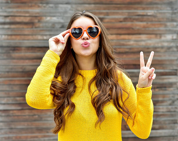 Beautiful brunette woman in sunglasses blowing lips kiss. wooden background. stock photo