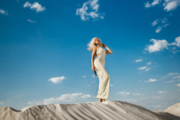 Beautiful caucasian blond woman in the desert in a sexy dress stock photo