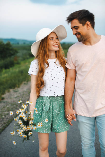 Beautiful closeup photo of couple on road holding flower. Springtime concept. Spring flowers. Love concept. Happy loving family. Summer concept. Road trip. stock photo