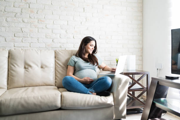 mooie aanstaande vrouw zitten met draagbare technologie - pregnant stockfoto's en -beelden