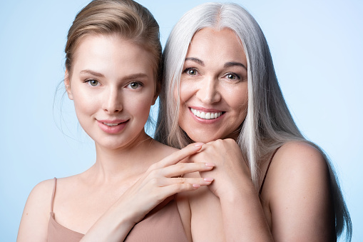 Beautiful female generations. Smiling young woman and mature mother hugging. Elderly gray-haired mum and adult daughter enjoying tender moment, cuddling, holding hands, happy family leisure together.