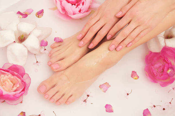 Beautiful female legs and feet. Woman is taking bath. Close up of female feet and hands in bath full of water and flowers. manicure stock pictures, royalty-free photos & images