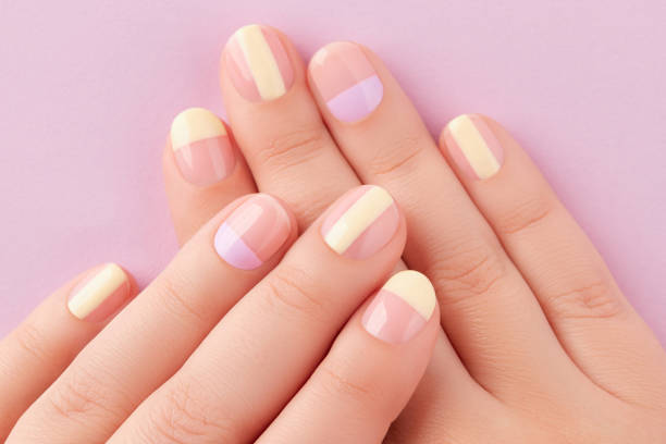 Beautiful females hands with manicure on lilac background. Trendy minimal spring summer nail design stock photo