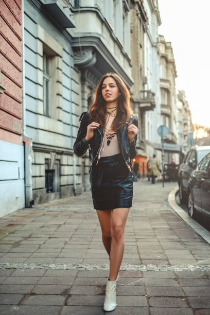 Beautiful girl in skirt with backpack walking on the sidewalk stock photo
