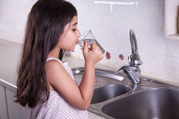 Beautiful girl in the nice white kitchen (series) One beautiful middle eastern little girl with pink dress and long dark brown hair and eyes on white kitchen, helping parents to wash dishes and drinking water and smiling.  cute arab girls stock pictures, royalty-free photos & images
