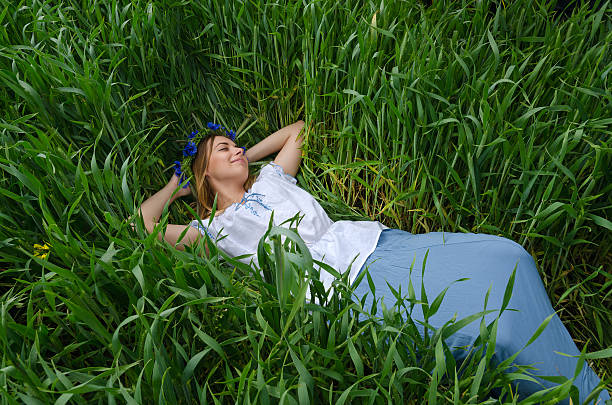 Beautiful girl lies in field among green ears of wheat stock photo