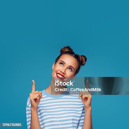 istock Beautiful girl pointing up presenting your product 1296735885