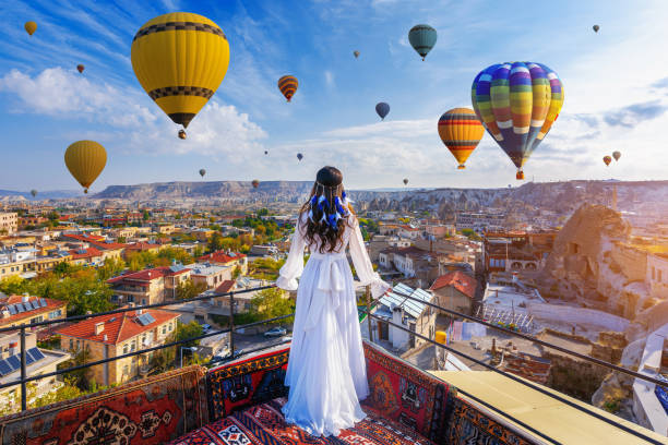 Beautiful girl standing on the hotel and looking to hot air balloons in Cappadocia, Turkey. stock photo
