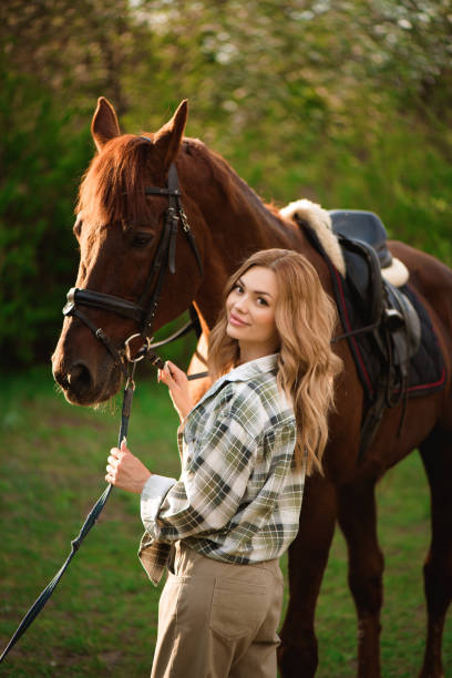 Beautiful girl with her horse and beautiful warm sunset in the spring forest. stock photo