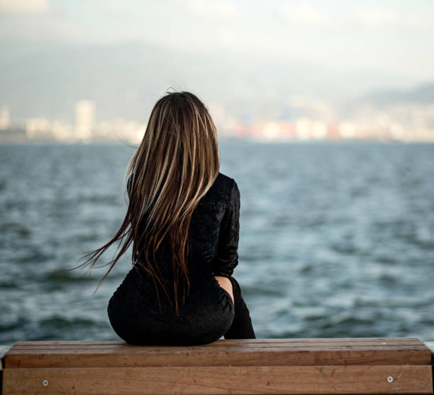 beautiful girl with long straight hair is sitting near sea beautiful girl with long straight hair is sitting near sea girls in very short dresses stock pictures, royalty-free photos & images