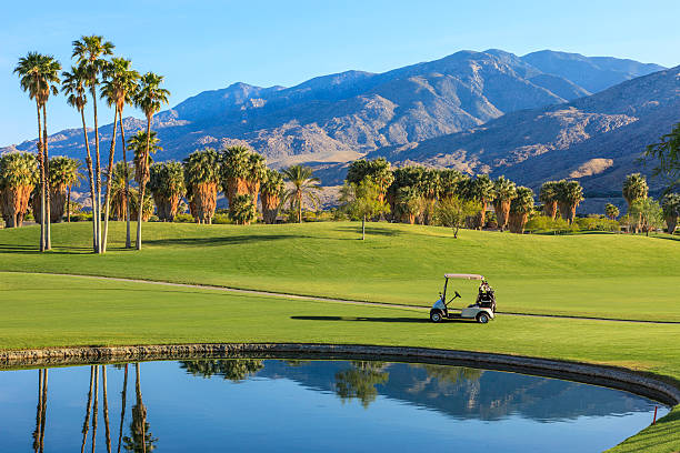 Beautiful golf course's lake and golf cart in California Late afternoon light cast a warm glow to a golf course in Palm Springs, California palm springs california stock pictures, royalty-free photos & images