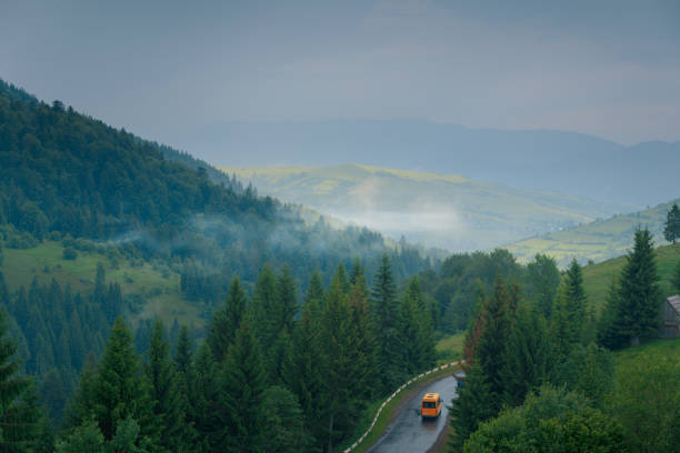 Beautiful green summer foggy mountains view with asphalt wet road after the rain and small bus moving on it. Beautiful green summer foggy mountains view with asphalt wet road after the rain and small bus moving on it. carpathian mountain range stock pictures, royalty-free photos & images
