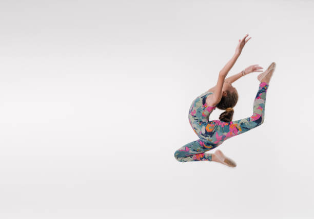 Beautiful gymnast athlete teenage girl  jumping in studio Beautiful gymnast athlete teenage girl doing exercise jumping in studio on white background doing the splits stock pictures, royalty-free photos & images