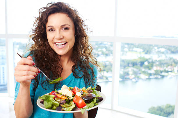 Beautiful happy female eating a salad stock photo
