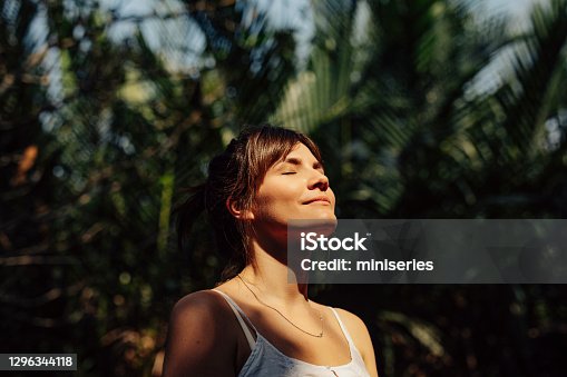 istock Beautiful Happy Woman Enjoying the Warm Sunlight in a Tropical Public Park 1296344118