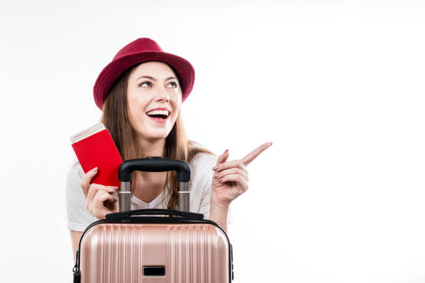 Beautiful happy woman sitting holding her luggage, passport, map and ticket for boarding. Air flight journey concept stock photo