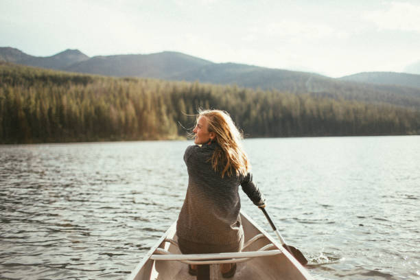 Beautiful healthy active woman canoeing on a lake at sunset stock photo