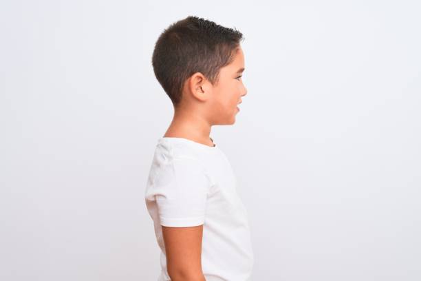 Beautiful kid boy wearing casual t-shirt standing over isolated white background looking to side, relax profile pose with natural face with confident smile. Beautiful kid boy wearing casual t-shirt standing over isolated white background looking to side, relax profile pose with natural face with confident smile. lateral surface photos stock pictures, royalty-free photos & images