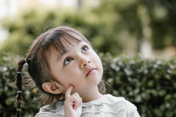 Beautiful kid playing Thinker with serious Portrait, pigtails, thinking, planning, positive emotion, Ideas, Inspiration, creativity, studying, learning, garden, nature, Asian and Indian Ethnicities cute thai girl stock pictures, royalty-free photos & images