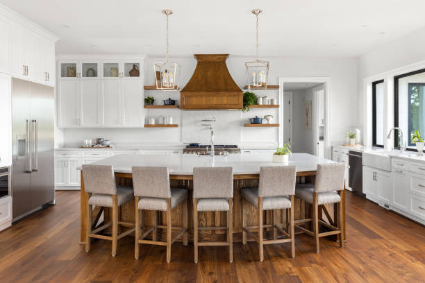 mooie keuken in nieuwe luxe huis met eiland, hanglampen, en hardhouten vloeren. - kookeiland stockfoto's en -beelden