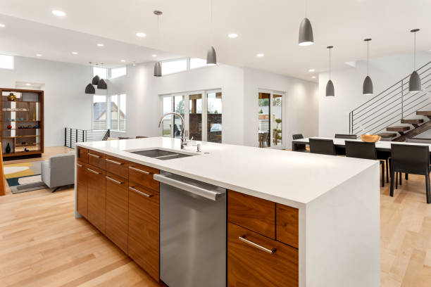 Beautiful kitchen in new luxury home with waterfall quartz island, pendant lights and hardwood floors. stock photo