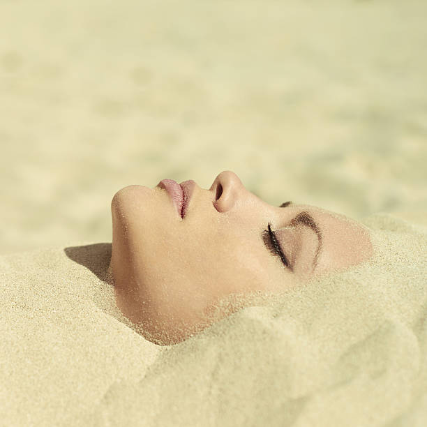 Beautiful lady buried in the sand stock photo