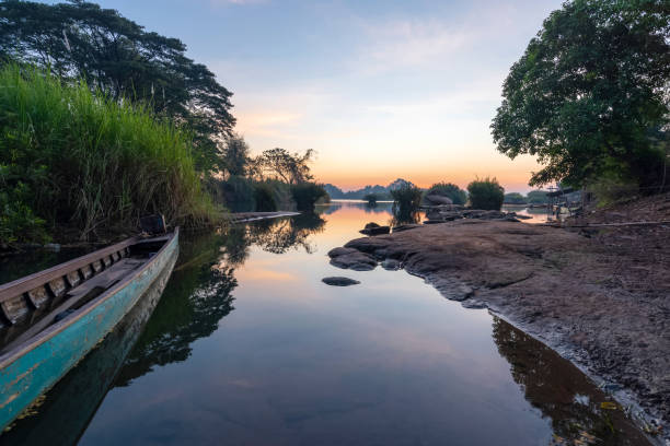 Beautiful landscape view of sunrise and old wooden boat drop nearly the river in front of guest house from Don Det the famous place for tourist to relaxing at Siphondon island, Laos. stock photo