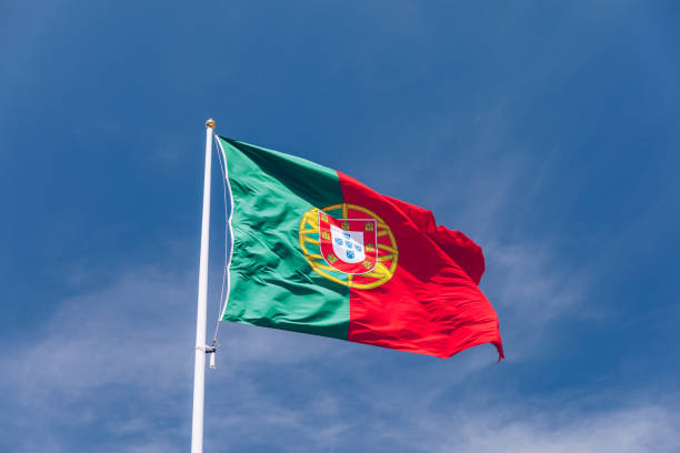 beautiful large portuguese flag waving in the wind against blue sky. portuguese flag waving against blue sky. flag of portugal waving, against blue sky - portugal flag imagens e fotografias de stock
