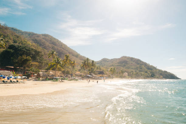 Beautiful Las Animas Beach Landscape in Mexico on Spring Day This is a horizontal color photograph of the Las Animas beach landscape near Puerto Vallarta, Mexico. Photographed on a sunny spring day. Incidental people are on the beach in the distance. Mountains rise above the shoreline. puerto vallarta stock pictures, royalty-free photos & images
