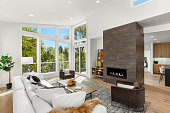 istock Beautiful living room interior with hardwood floors and fireplace in new modern luxury home. Features wall of windows and abundant natural light. 1398702648