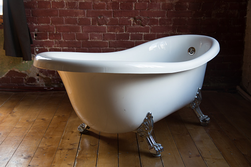 Beautiful luxury vintage bath on a wooden floor against a brick wall background.