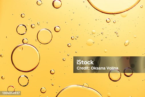istock Beautiful macro photo of water droplets in oil with a yellow background. 1304044937