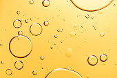 istock Beautiful macro photo of water droplets in oil with a yellow background. 1304044937