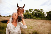 istock Beautiful mature woman enjoying with closed eyes her brown arabian mare in the free nature 1328868643