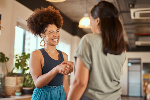Beautiful mixed race creative business woman shaking hands with a female colleague. Two young female african american designers making a deal. A handshake to congratulate a coworker on their promotion stock photo